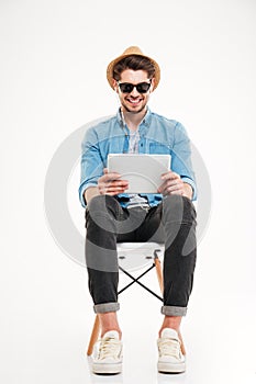 Handsome smiling male using tablet and sitting on the chair