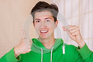 Handsome smiling man with a happy face holding a menstruation cotton tampon with his thumb up, approving the use of
