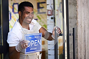 Handsome smiling man hold open sign in shop