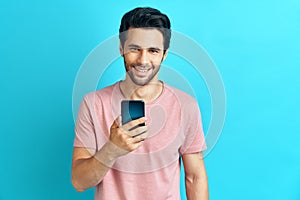 Handsome smiling man holding mobile phone and looking to camera