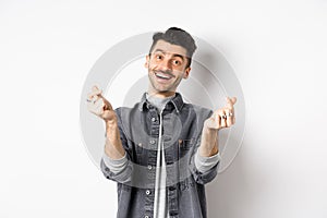 Handsome smiling man showing hand hearts and looking with love at camera, standing on white background