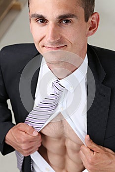 Handsome smiling man in tie rip clothes off torso showing abs.