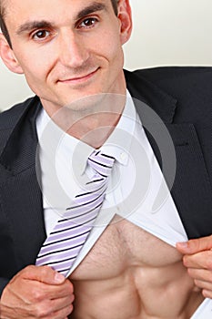 Handsome smiling man in tie rip clothes off torso showing abs.