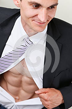 Handsome smiling man in tie rip clothes off torso showing abs.