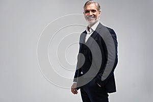 Handsome smiling middle-aged man in suit posing against grey background