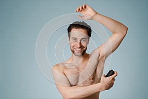 Handsome smiling nude man spraying deodorant