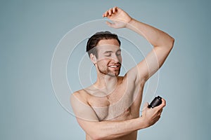 Handsome smiling nude man spraying deodorant