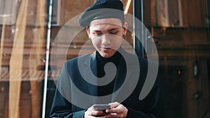 Handsome smiling Startup Businessman in beret using mobile Phone. Young man texting Messages, chatting on his Smartphone