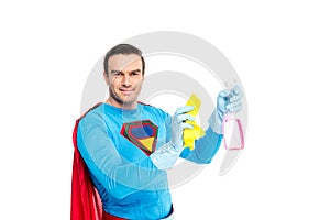 handsome smiling superman holding rag and spray bottle with detergent