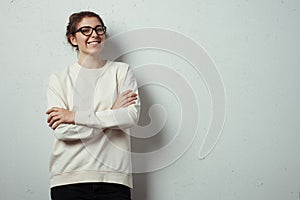 Handsome smiling woman hipster wearing blank sweater and eye glasses. Grunge wall with cracks background