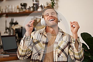 Handsome smiling young man, digital nomad, sitting in co-working open space, working in coffee shop, singing and