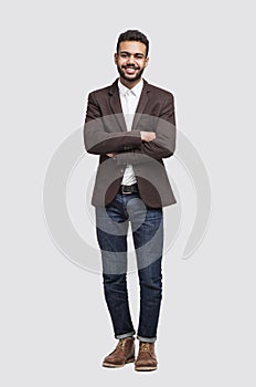 Handsome smiling young man full length studio portrait, isolated on gray background
