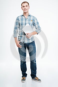 Handsome smiling young man standing and holding laptop