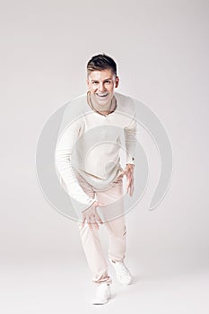 Handsome young man in a white sweater and pants photo