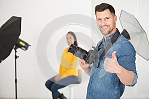handsome smiling young photographer showing thumb up photo