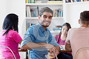 Handsome spanish male student with group of students at library of university