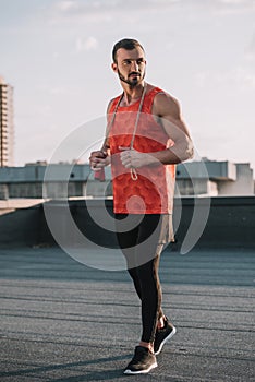 handsome sportive man with jumping rope and red shirt looking away