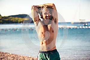 Handsome sports man doing stretching before run at the beach