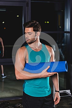 handsome sportsman holding yoga mat