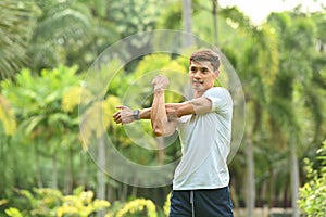 Handsome sportsman stretching muscle before workout session at the park in early morning. Healthy lifestyle concept