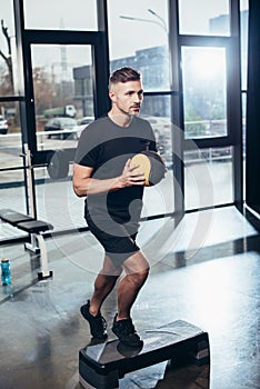 handsome sportsman training on step platform with medicine ball photo