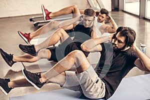 handsome sportsmen simultaneously doing sit ups