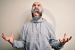 Handsome sporty bald man with beard wearing sweatshirt standing over pink background crazy and mad shouting and yelling with