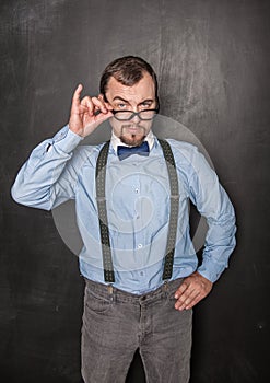 Handsome strict teacher in eyeglasses looking at you on