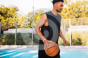 Handsome Strong man is holding ball on the basketball court.Man with a ball,sport outfit