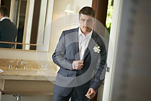 Handsome and strong man putting on official suit.