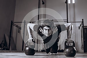 Handsome Strong man workout at gym, strength pushup exercise with Kettlebell.