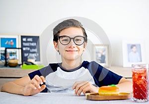 A handsome student schoolboy 8-9 years old wearing black glasses having snack