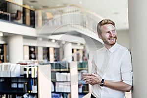 Handsome student smiling in library