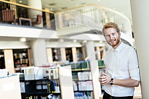 Handsome student smiling in library