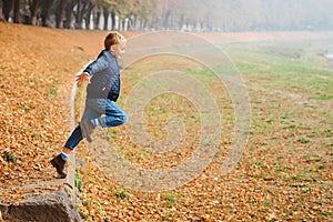 Handsome stylish boy having fun outdoors. Happy kid jumping on autumn walk. Autumn fashion. Fashion, family and autumn season