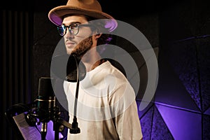 Handsome stylish male singer recording new song in modern studio. Portrait of young musician in studio