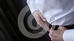 Handsome stylish man dressed in modern formal clothes buttoning jacket. Close up of hands of guy in blue jacket, white