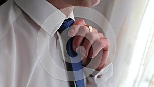 Handsome stylish man dressed in modern formal clothes buttoning jacket. Close up of hands of guy in blue jacket, white