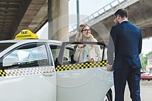 handsome stylish man opening car door to smiling blonde woman sitting