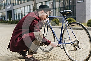 handsome stylish man repairing bicycle