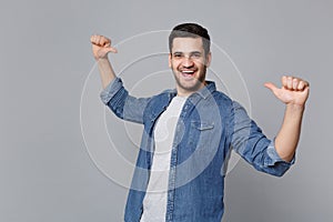 Handsome stylish unshaven young man in denim jeans shirt posing isolated on grey background studio portrait. People