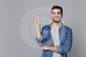 Handsome stylish unshaven young man in denim jeans shirt posing isolated on grey background studio portrait. People
