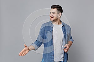 Handsome stylish unshaven young man in denim jeans shirt posing isolated on grey background studio portrait. People