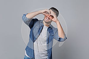 Handsome stylish unshaven young man in denim jeans shirt posing isolated on grey wall background studio portrait. People