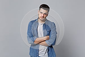 Handsome stylish unshaven young man in denim jeans shirt posing isolated on grey wall background studio portrait. People