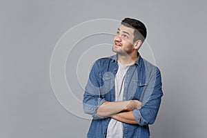 Handsome stylish unshaven young man in denim jeans shirt posing isolated on grey wall background studio portrait. People
