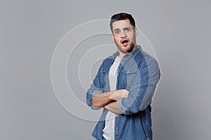 Handsome stylish unshaven young man in denim jeans shirt posing isolated on grey wall background studio portrait. People