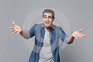 Handsome stylish unshaven young man in denim jeans shirt posing isolated on grey wall background studio portrait. People