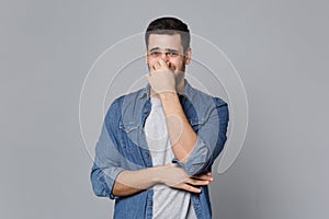 Handsome stylish unshaven young man in denim jeans shirt posing isolated on grey wall background studio portrait. People