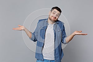 Handsome stylish unshaven young man in denim jeans shirt posing isolated on grey wall background studio portrait. People